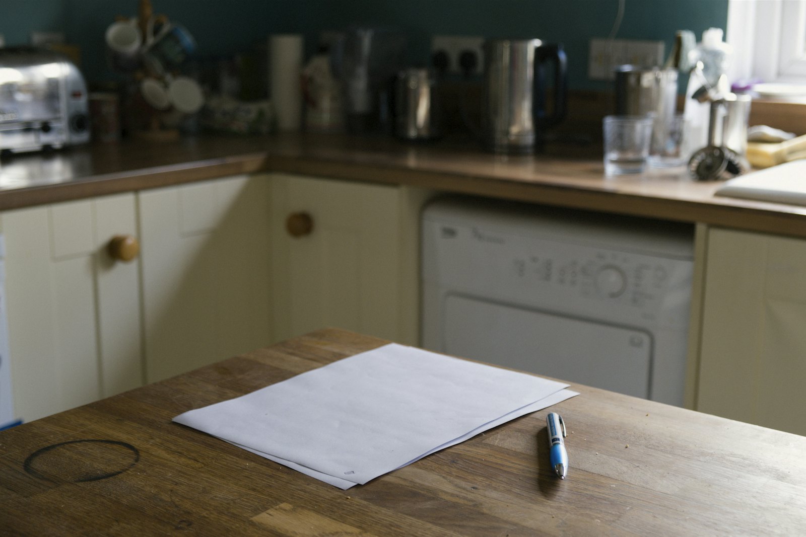 Une feuille et un stylo posés sur la table d’une cuisine